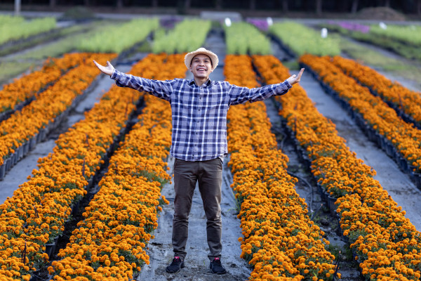 large-asian-gardener-is-welcoming-people-into-his-cut-flower-farm-full-of-orange-marigold-for-medicinal-and-garnish-in-the-fine-dining-restaurant-business