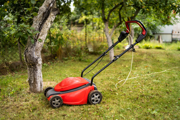 2400-red-lawn-mower-outdoor-in-the-backyard-green-grass-and-fruit-trees-background-gardening-concept