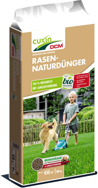 Produktbild von Cuxin DCM Rasen-Naturdünger Minigran 20kg mit Verpackung, Markenlogo, Produktinformationen und Bild eines Kindes, das Rasen mäht, und ein Hund daneben auf einer Wiese.